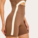 Detalhe-lateral-do-macaquinho-fitness-marrom-com-faixa-clara-e-recorte-na-cintura.