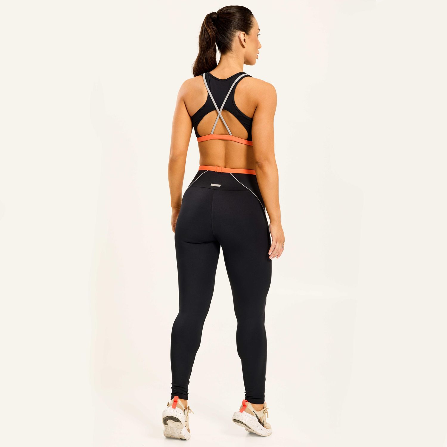 vista-traseira-de-conjunto-fitness-preto-com-legging-de-cos-laranja-e-acabamento-anatomico