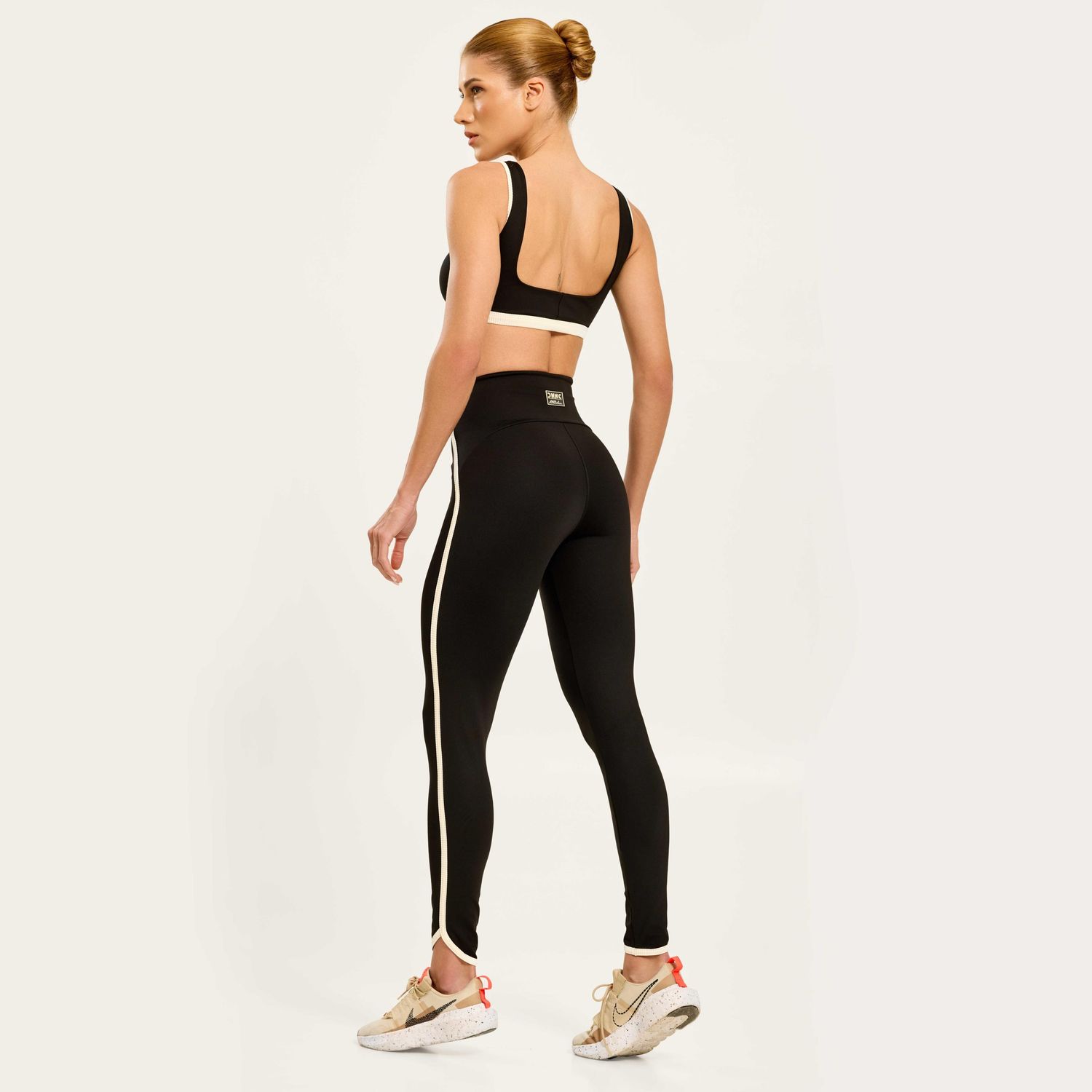 vista-traseira-de-conjunto-fitness-preto-com-legging-de-cos-alto-e-detalhe-claro-que-contorna-o-tornozelo