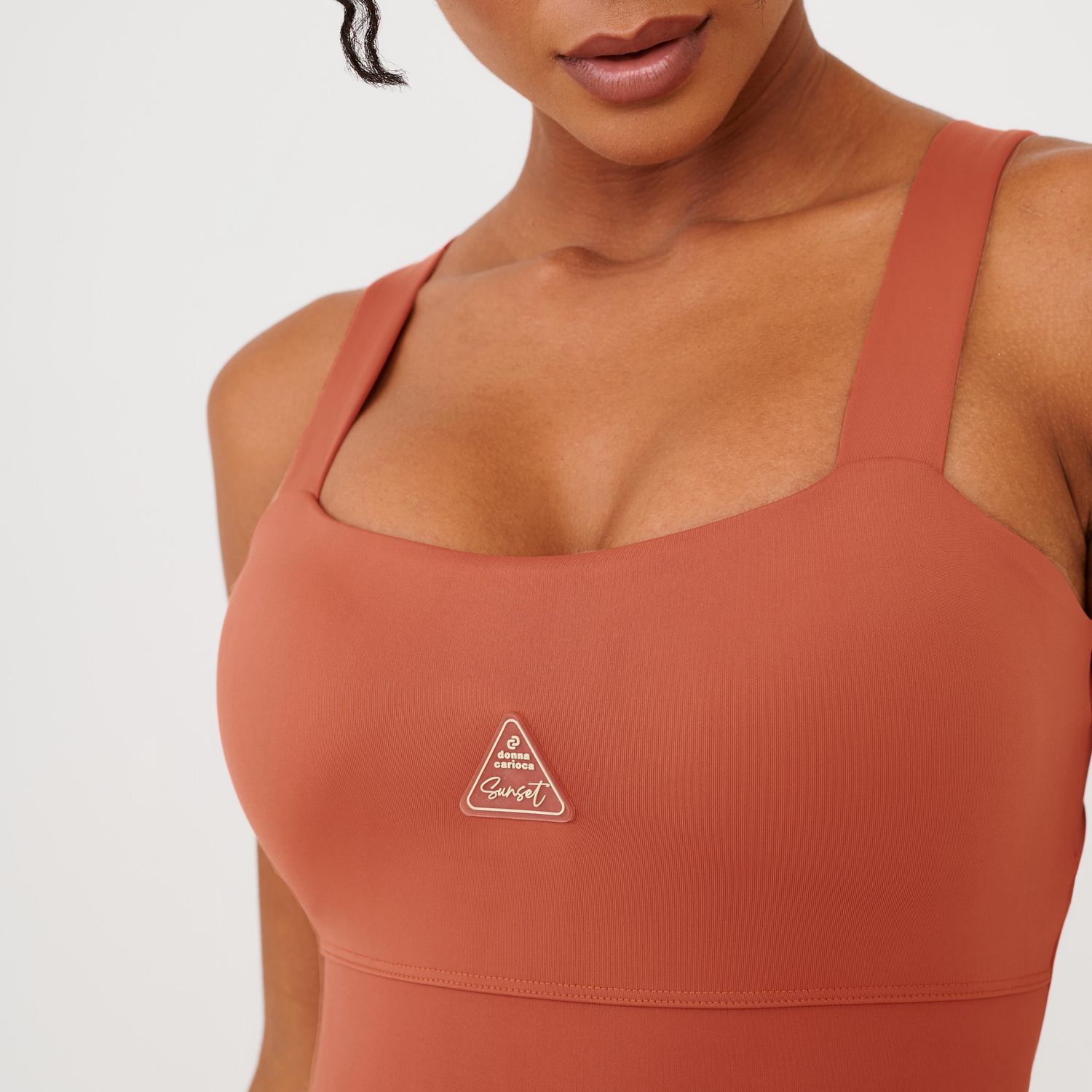 Detalhe-do-busto-do-macaquinho-fitness-terracota-com-logo-frontal-e-tecido-liso.