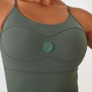 Detalhe-do-busto-do-macaquinho-fitness-verde-com-logo-redondo-em-relevo-e-costuras-modeladoras.